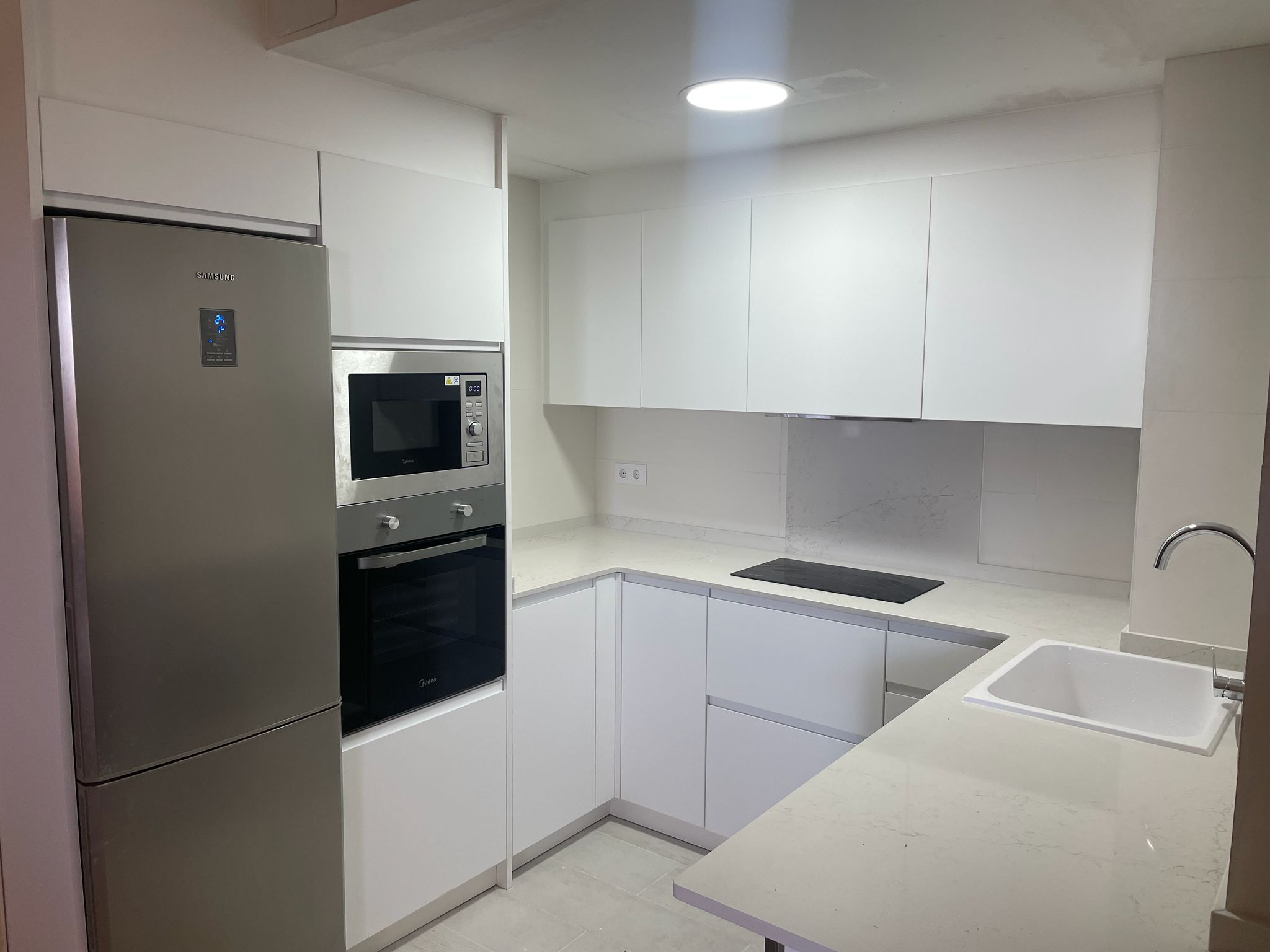 Cocina reformada por Vie — blanca, con encimera de cuarzo y electrodomésticos integrados